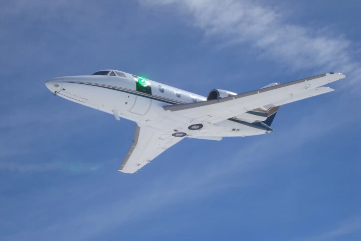 A green low-power laser beam passes through the turret on a research aircraft