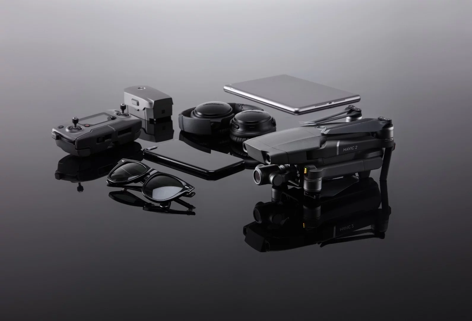 A photographer's travel kit: a smartphone, a tablet, a Mavic 2 Zoom drone and a pair of sunglasses