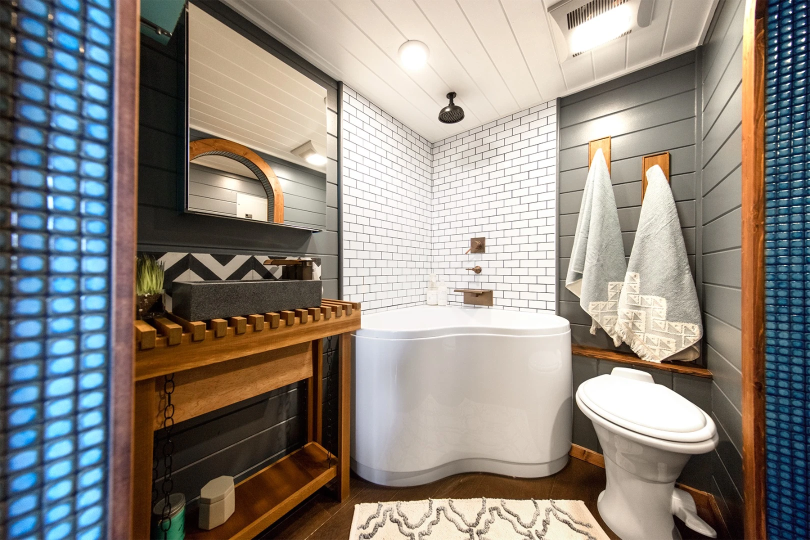 The Tiny Adventure Home's bathroom includes a corner soaking tub/shower unit