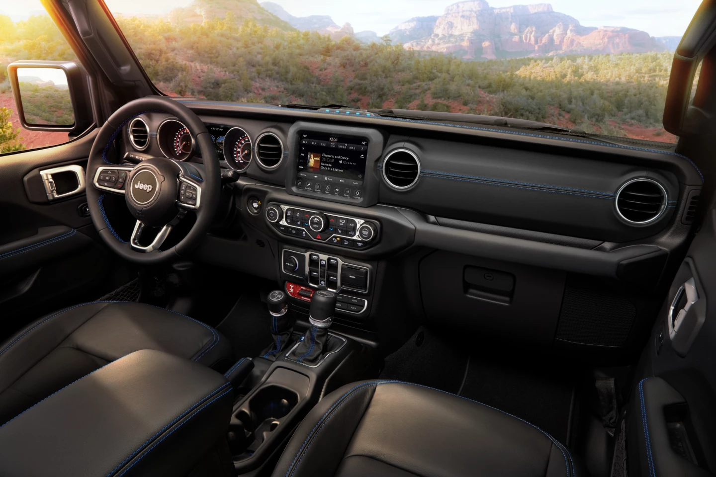 The interior of the 2021 Jeep Wrangler Rubicon 4xe is largely unchanged from that of the standard Wrangler models, with the exception of the blue stitching and details