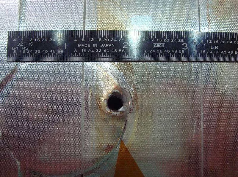 Entry hole from impact of space debris on Shuttle Endeavor - the entry hole was about a centimeter in size, while the exit hole was several centimeters (Photo: NASA)