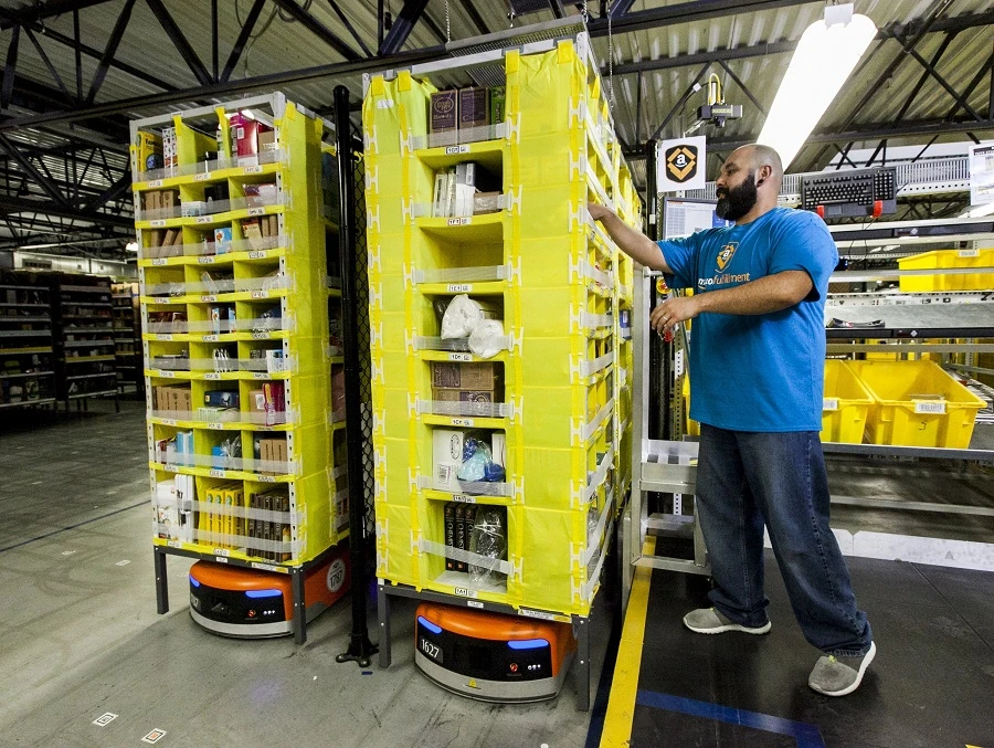An Amazon employee picks items from a Kiva robot