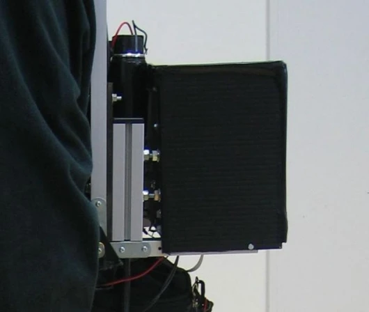 The motors in the backpack drive the powered shoes via flexible shafts