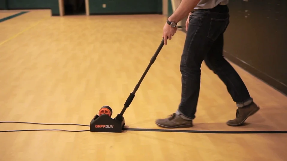 The GaffGun straightens, centers and tapes down cords and cables