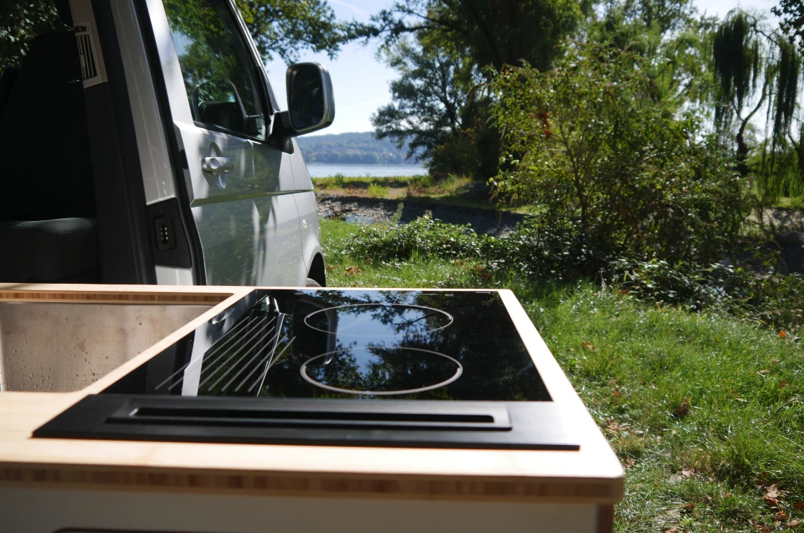 The kitchen slides out, offering its dual-burner stove and stainless steel sink for outdoor meal prep