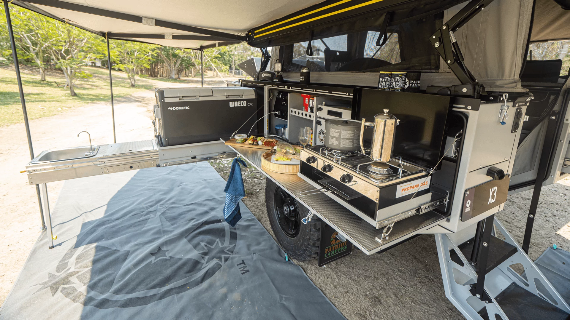 The L-shaped outdoor kitchen includes a long slide-out, fold-down worktop and dual-burner gas stove