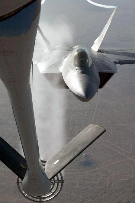 A modified KC-135 Stratotanker sprays water on an F/A-22 during an airborne ice test here. The Raptor was the first aircraft to use the 'rain and ice tanker' for testing.