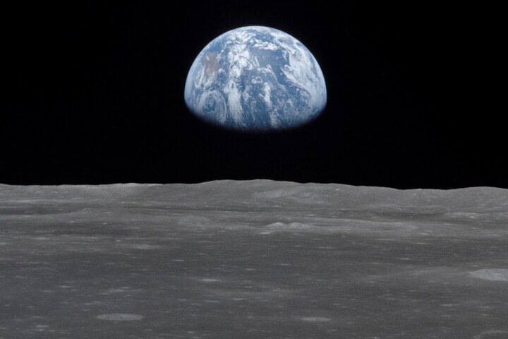 1969 photo of the lunar surface, with Earth rising on the horizon