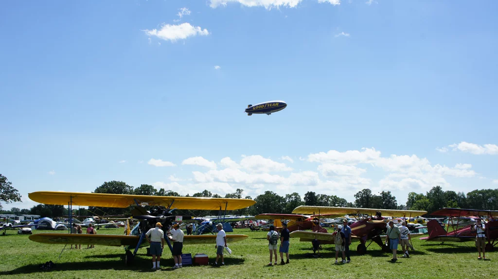 The Goodyear Blimp lies above crowds at AirVenture 2010