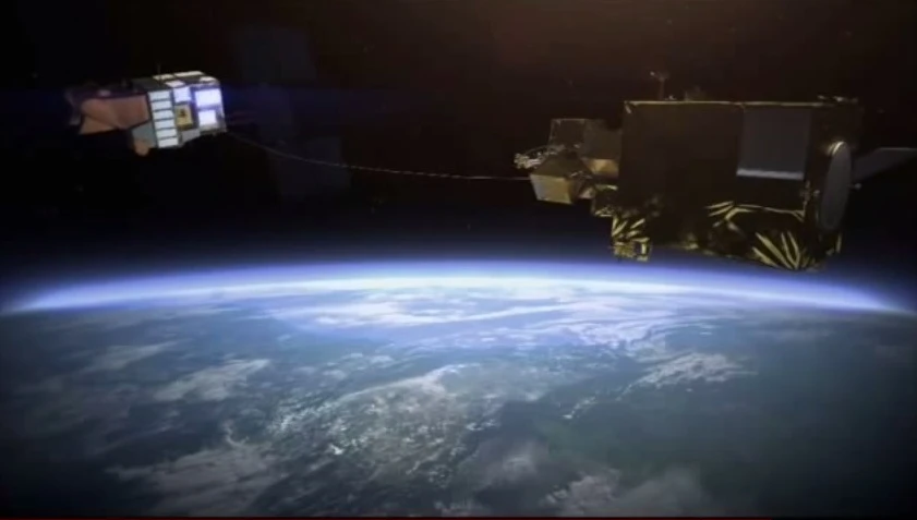 Artist's concept of a derelict satellite being reeled in after being harpooned by the e.DeOrbit satellite (Image: Airbus Defence and Space)