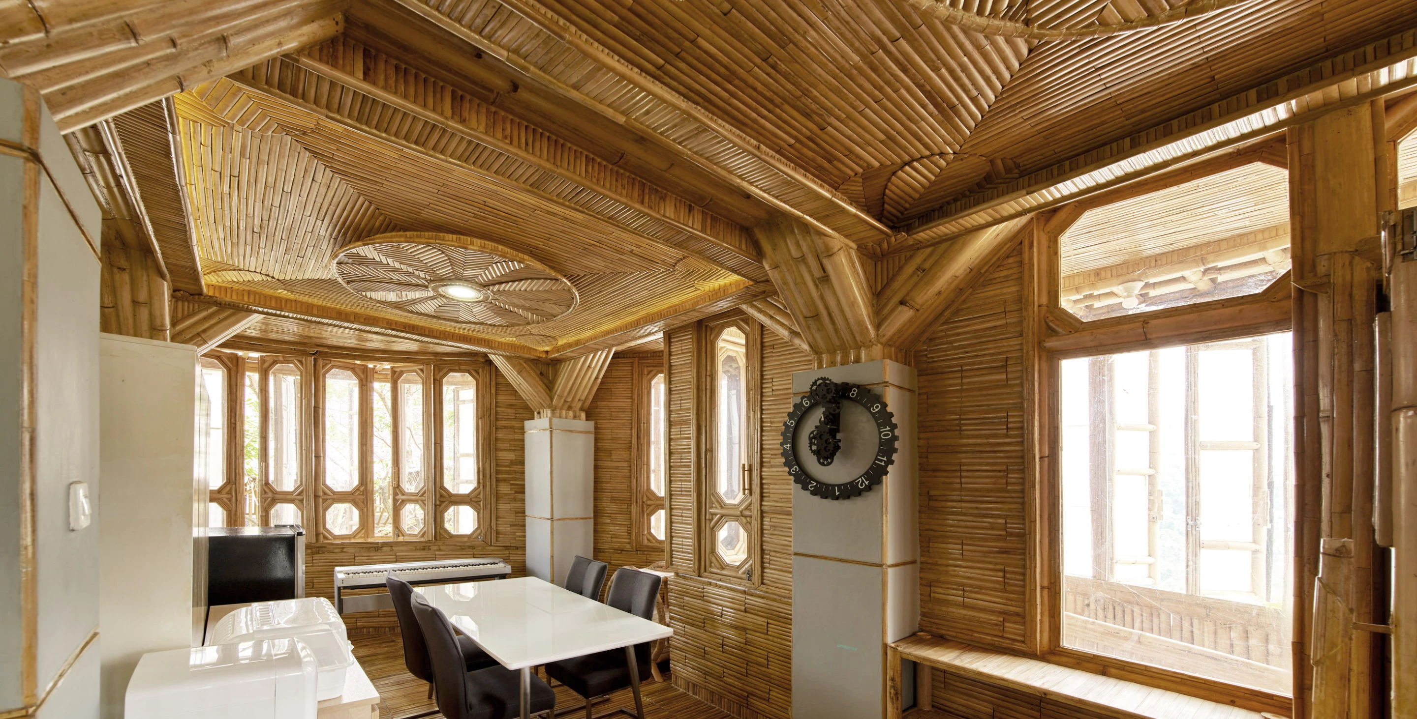 Sumarah, which is the name of the house, includes a dining area and kitchen. The modern white appliances contrast with the traditional bamboo