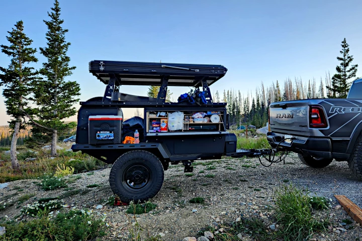 The Taxa Outdoors Woolly Bear Overland camp trailer, with its galley and an extra cooler open for snacks during camp setup