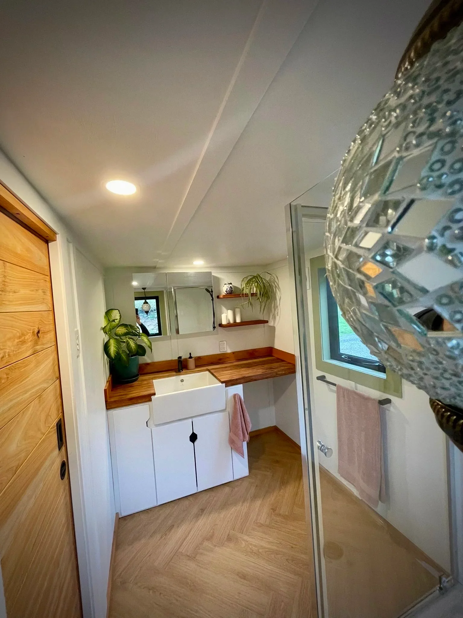 The Redwood's bathroom contains a glass-enclosed shower and a vanity sink that doubles as a laundry area