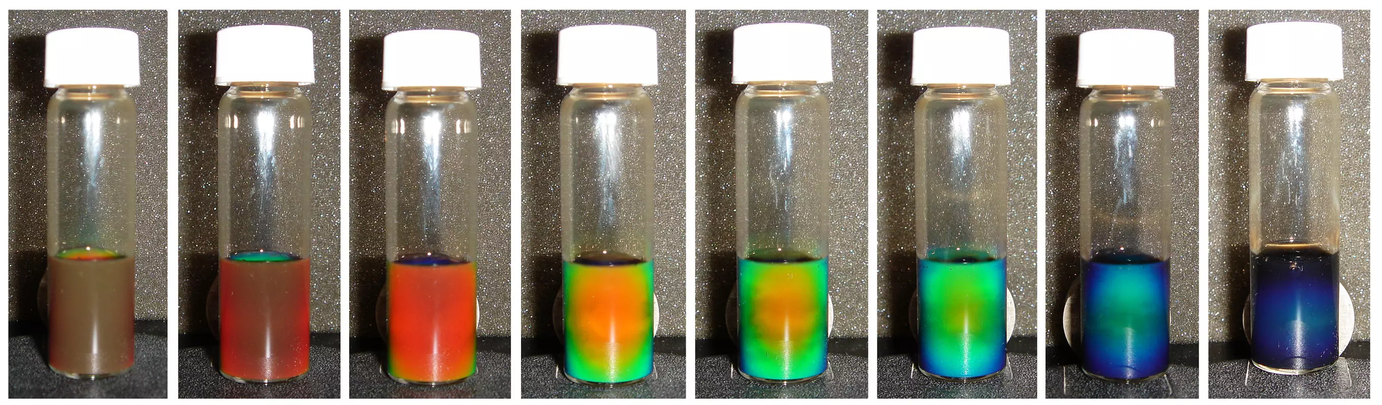 A solution of iron oxide in water changing color under a magnetic field, with increasing strength of the field from left to right (Photo: Yin laboratory, UCR)
