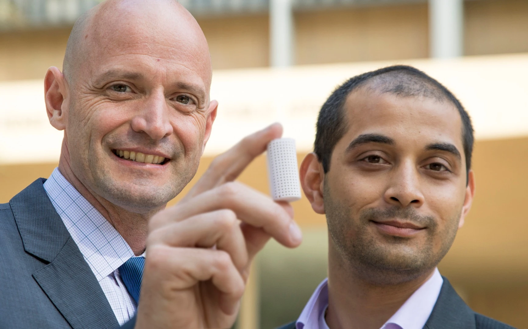 J.R. DeShazo (left) and Gaurav Sant show off a sample of the new building material they have created to replace conventional concrete