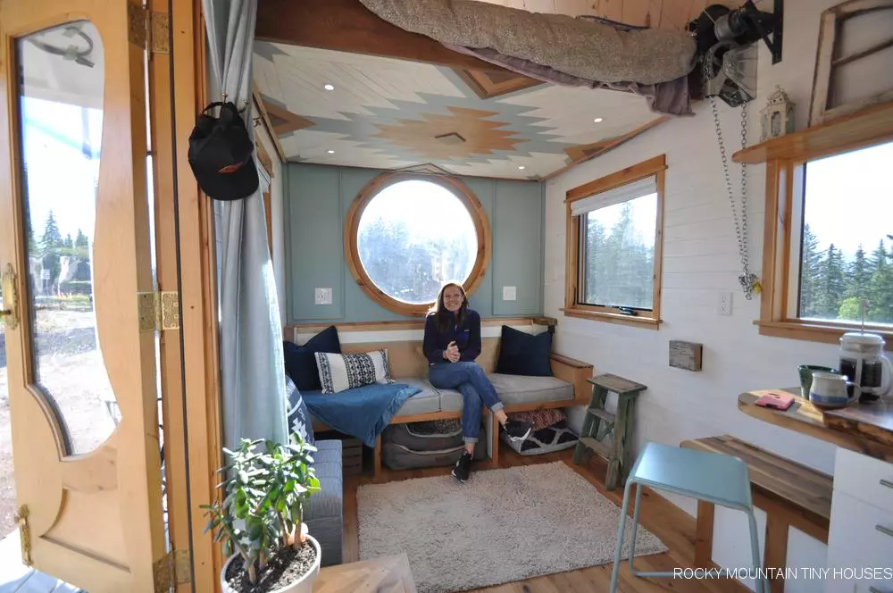 The San Juan Tiny House's living room/sleeping area has generous glazing, including a large circular window
