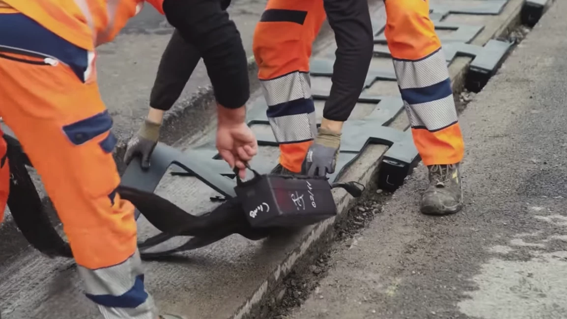 Workers place down inductive charging coils as the Arena Del Futuro is constructed