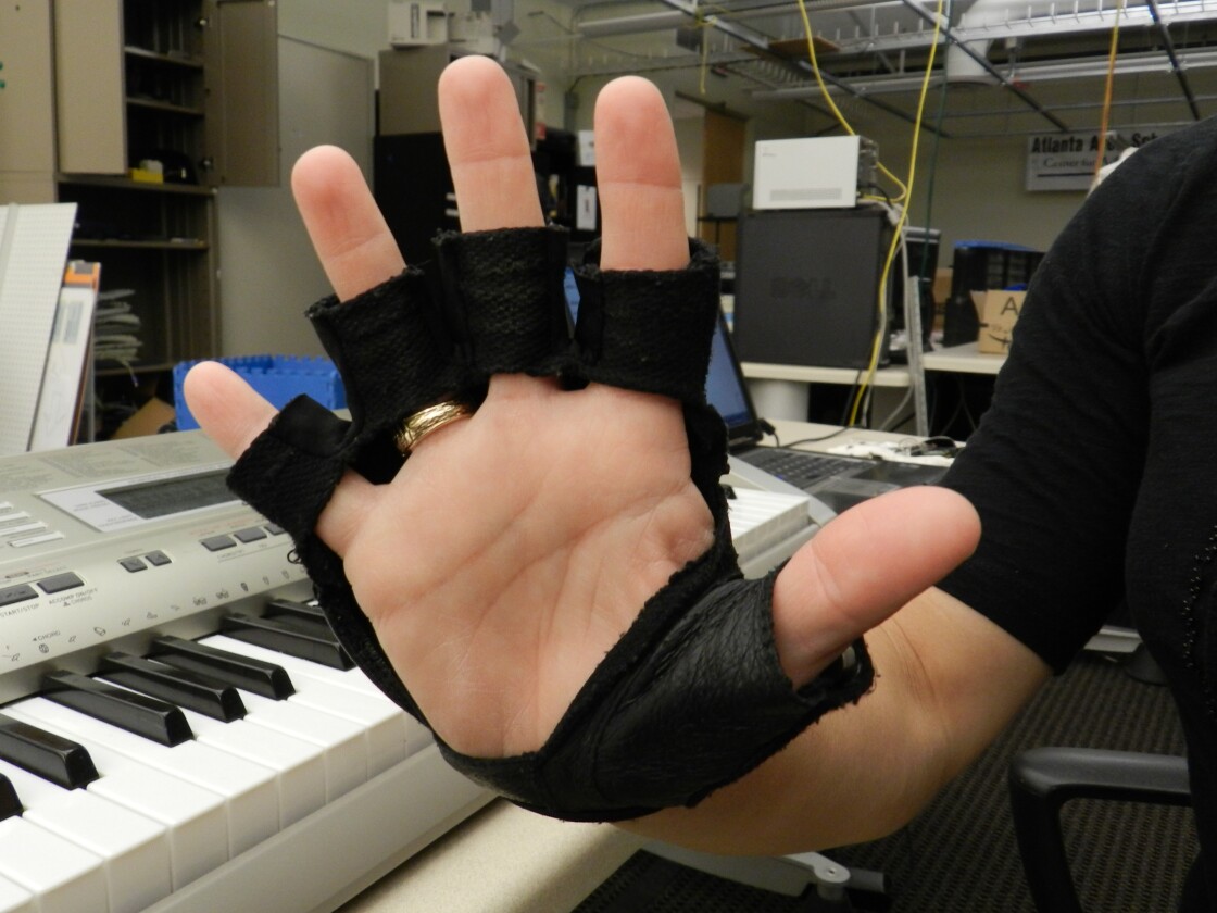 The MMT glove vibrates to indicate which finger to tap the piano keyboard with