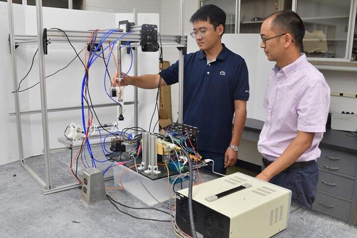 Asst. Prof. Long He (right) and visiting doctoral student Mingsen Huang with the prototype robot