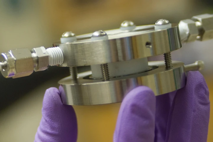 An experimental lithium-air battery developed at MIT has inlet and outlet on the sides to provide a flow of air, providing oxygen for the battery's operation (Image: Patrick Gillooly/MIT)