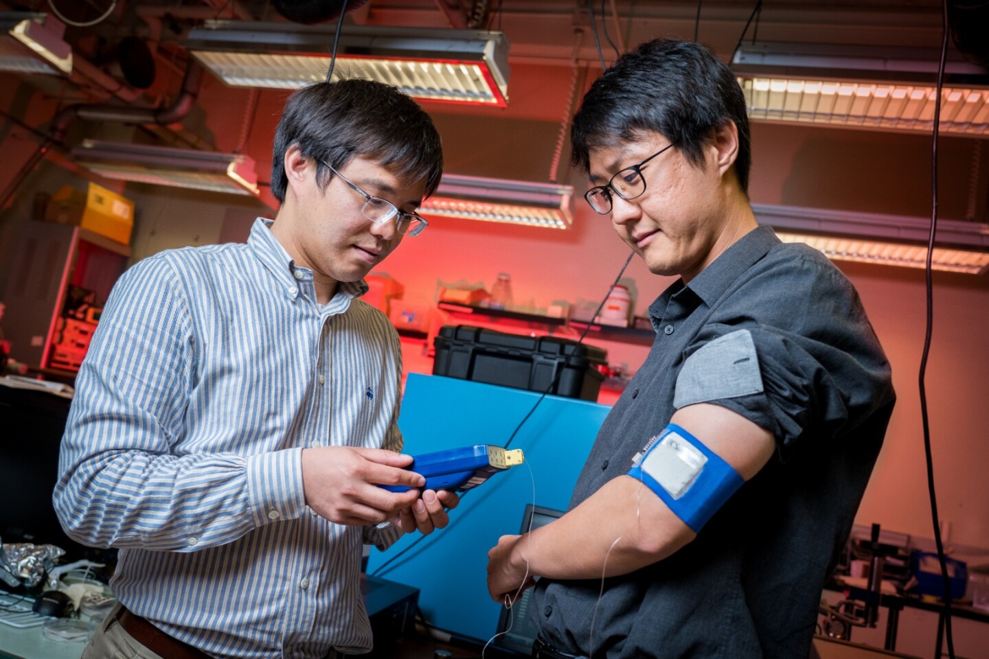 Study lead Renkun Chen, a professor of mechanical and aerospace engineering at UC San Diego, tests the armband prototype on study author Sahngki Hong's upper arm
