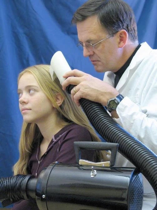 University of Utah biologist Dale Clayton demonstrates the the latest prototype of the LouseBuster on his daughter, Miriam. The new, chemical-free treatment kills almost all louse eggs and enough hatched lice to prevent them from reproducing, effectively