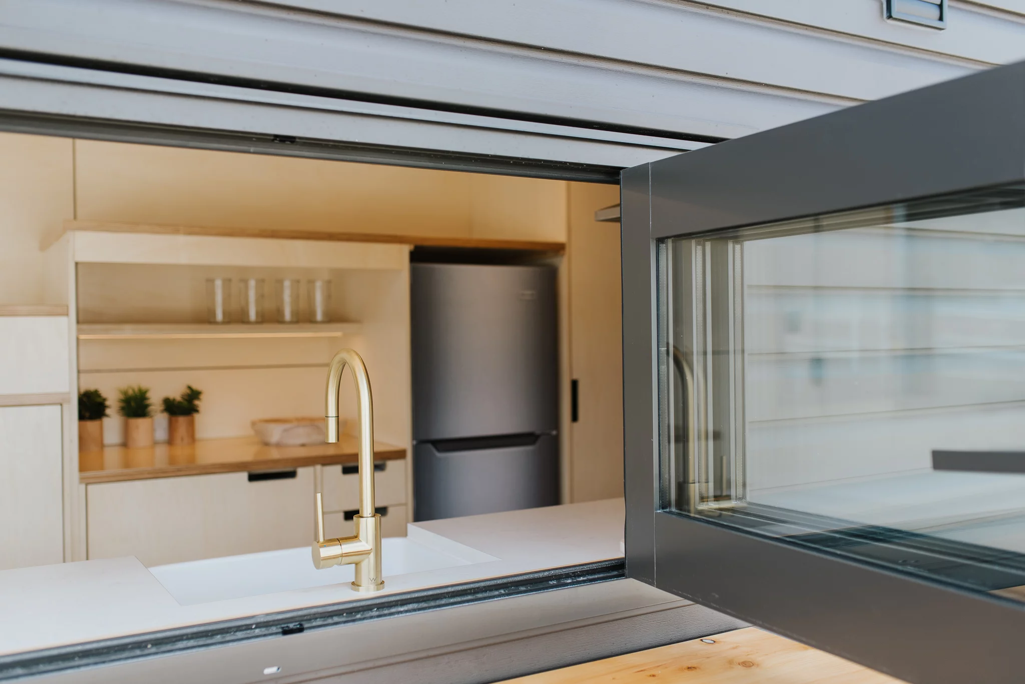 The Hilltop Tiny House features bifold windows that open onto an exterior shelf