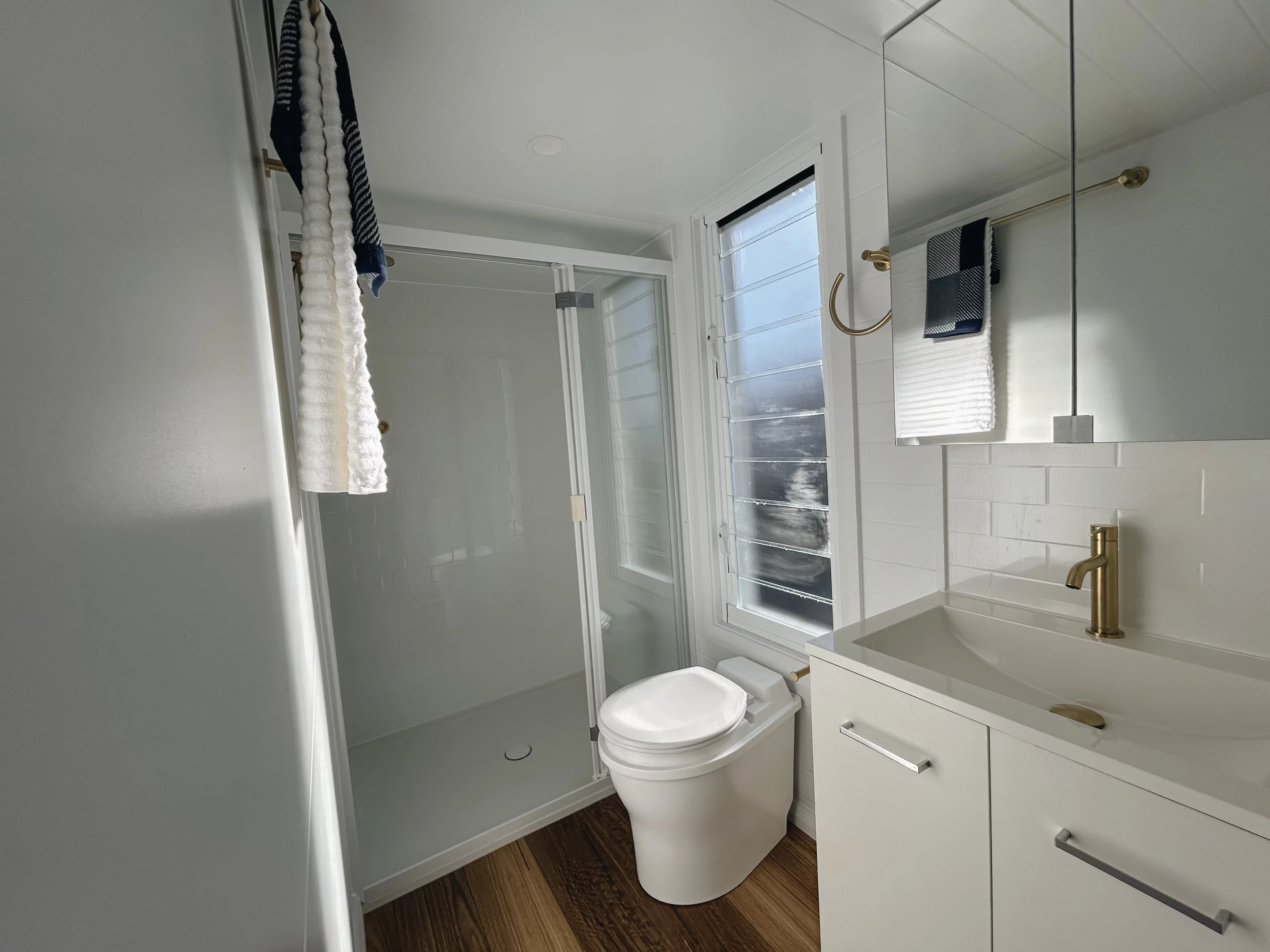 The Joely's bathroom includes a vanity sink, shower, and a flushing or composting toilet, plus a little more storage