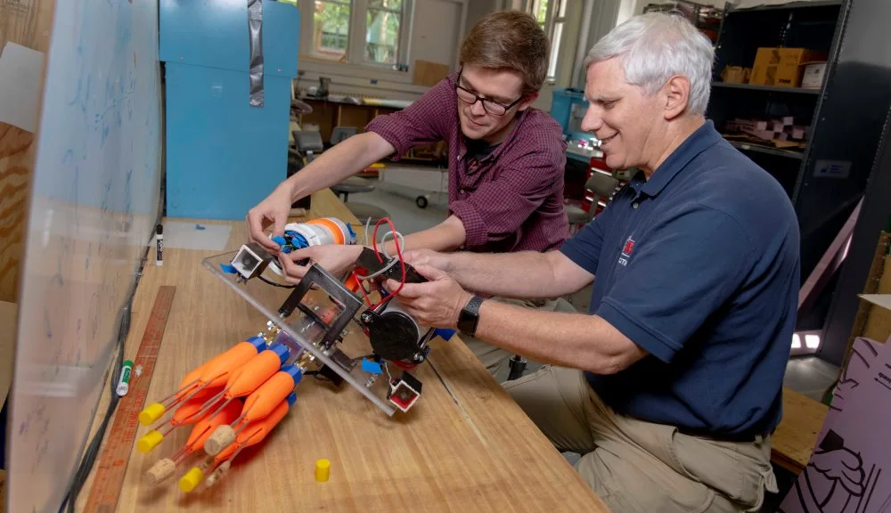 William Godsey ’18, left, and Bradley Miller, associate director of WPI’s Robotics Resource Center, examine the lionfish harvesting robot built by Godsey and his project team