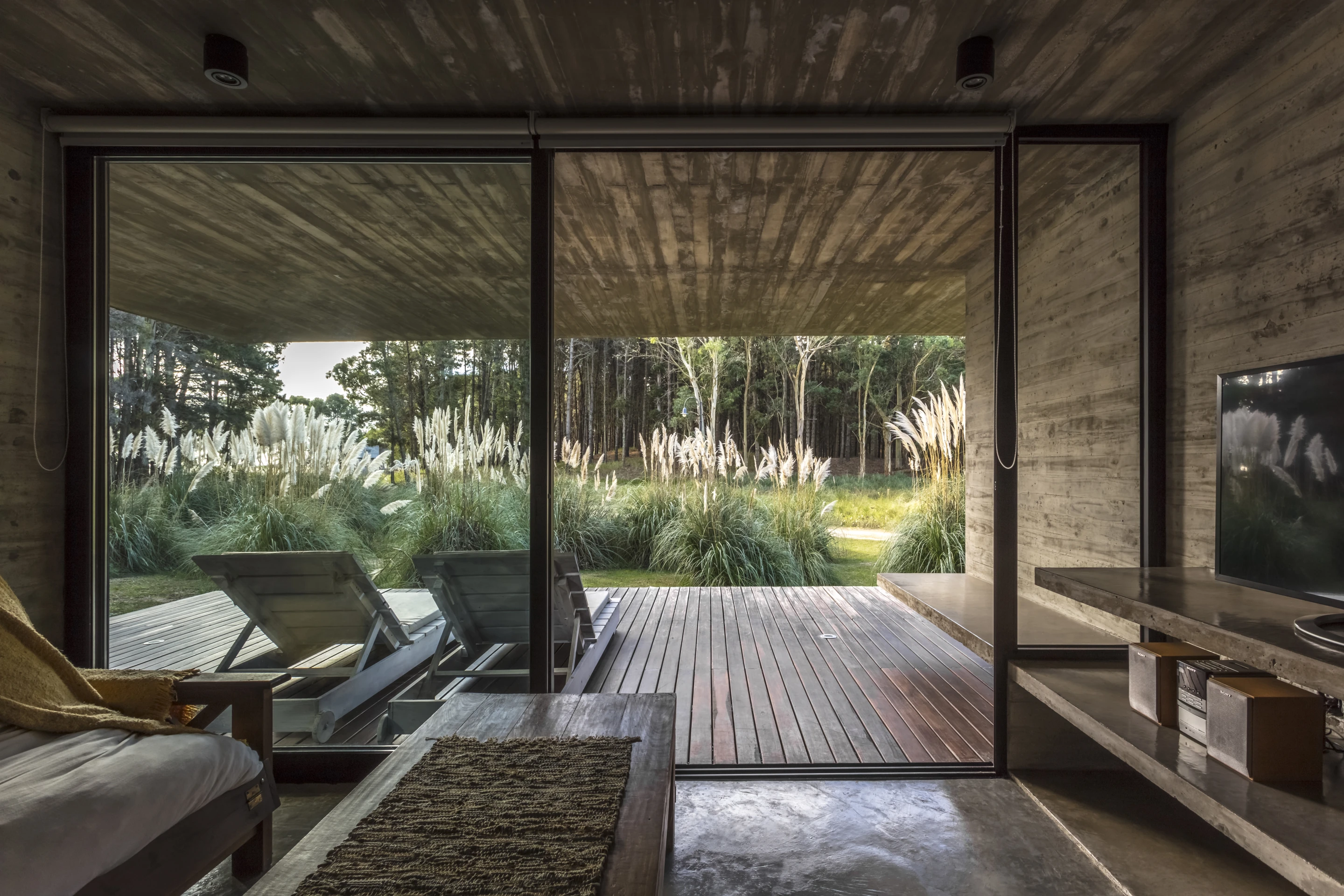 A living area opens up to a covered balcony in the Forest House, by Besonias Almeida