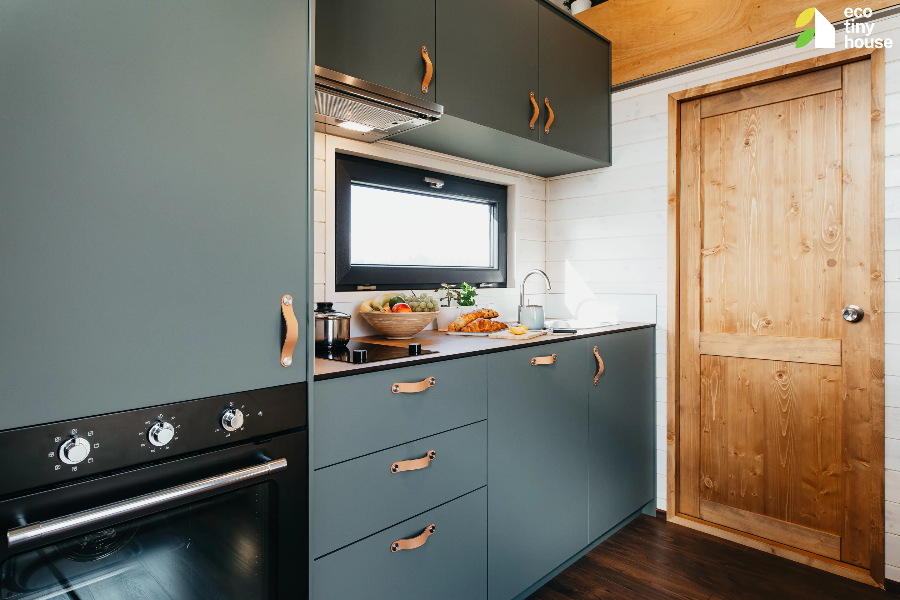 The Tiny Getaway's kitchen includes an oven, an induction cooktop, a sink, and a dishwasher