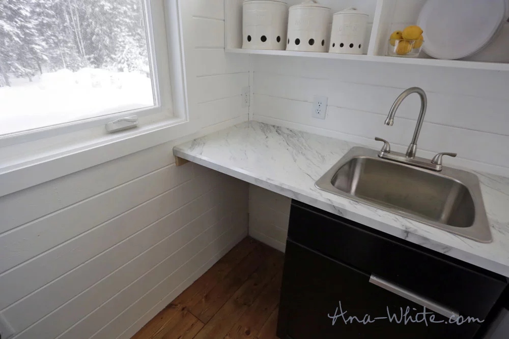 This space for the Open Concept Rustic Modern Tiny House's washer/dryer is usually covered by a kitchen unit on wheels