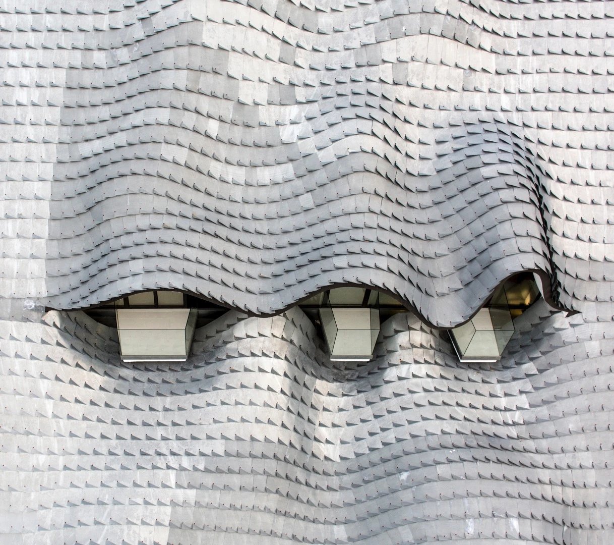 The roof comprises a double curved concrete shell packed with insulation and clad in handmade (and hand-placed) zinc roof tiles