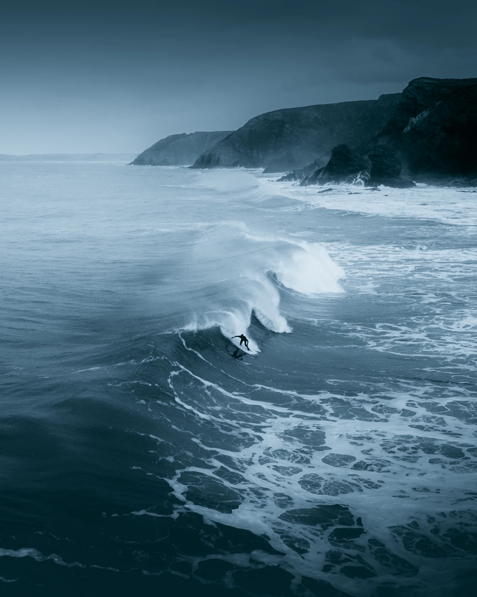 'A lone surfer braving the winter cold on the Cornish North Coast', St. Agnes, Cornwall, UK