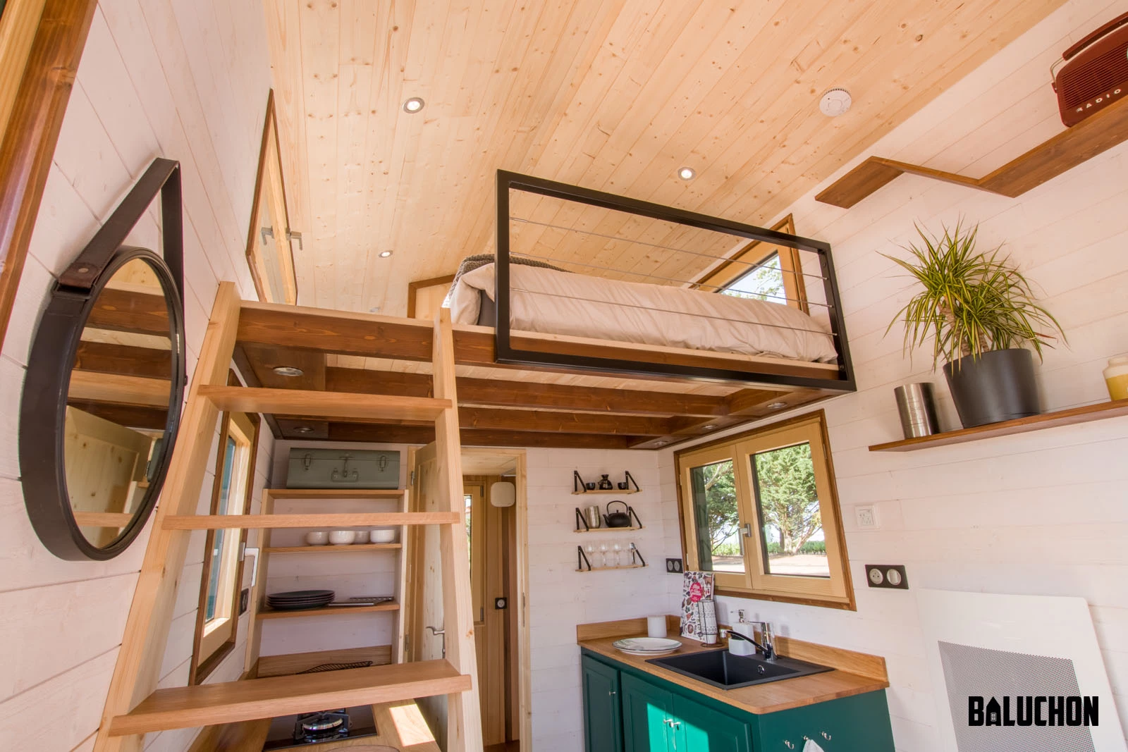 A wooden ladder leads up to the Hauméa tiny house's bedroom