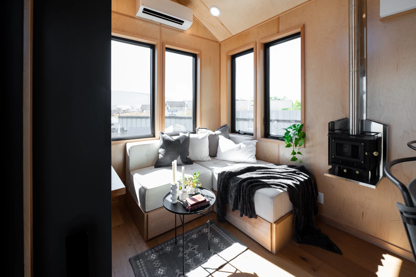 The living room includes an L-shaped sofa with integrated storage, plus a small wood-burning stove