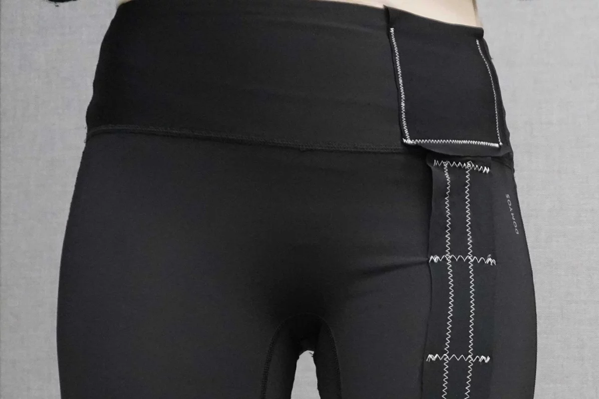 Close up of black leggings being worn that have white zigzag stitching attaching a strip of black fabric to them
