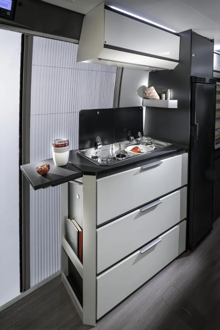 A simple kitchen block includes a dual-burner stove, sink, folding worktop and drawers