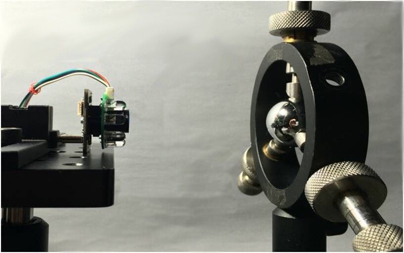 A pupillometer testing setup, with the device on the left and an eye model on the right