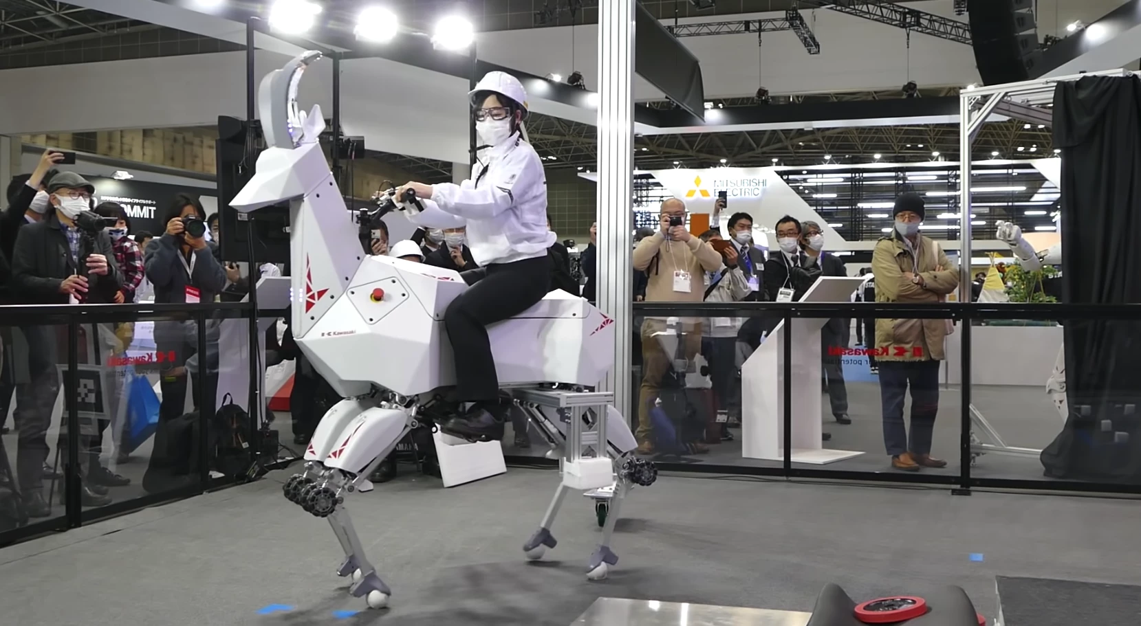 A Kawasaki team member rides "BEX," the robot quadruped, at iREX 2022