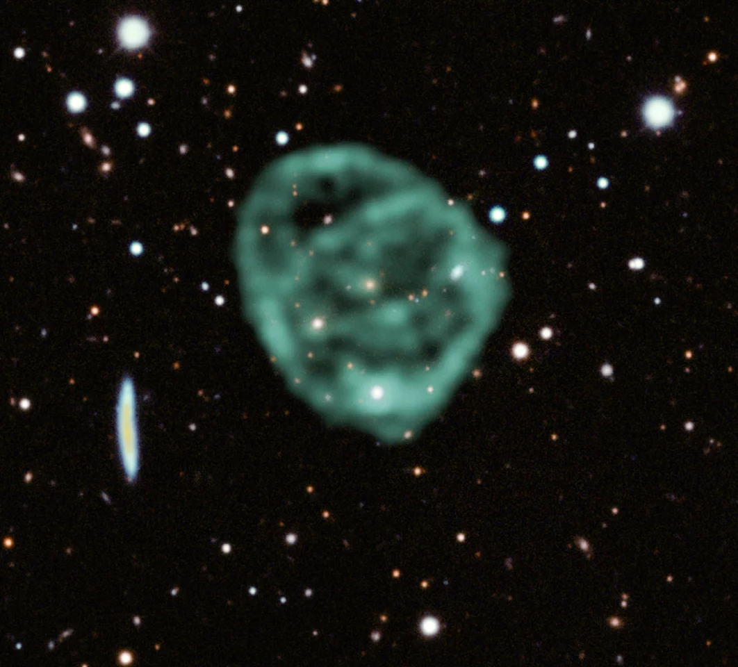 The new image of an odd radio circle (ORC). Radio images captured by the MeerKAT radio telescope are highlighted in green, while the background was filled out with optical and near-infrared data from the Dark Energy Survey