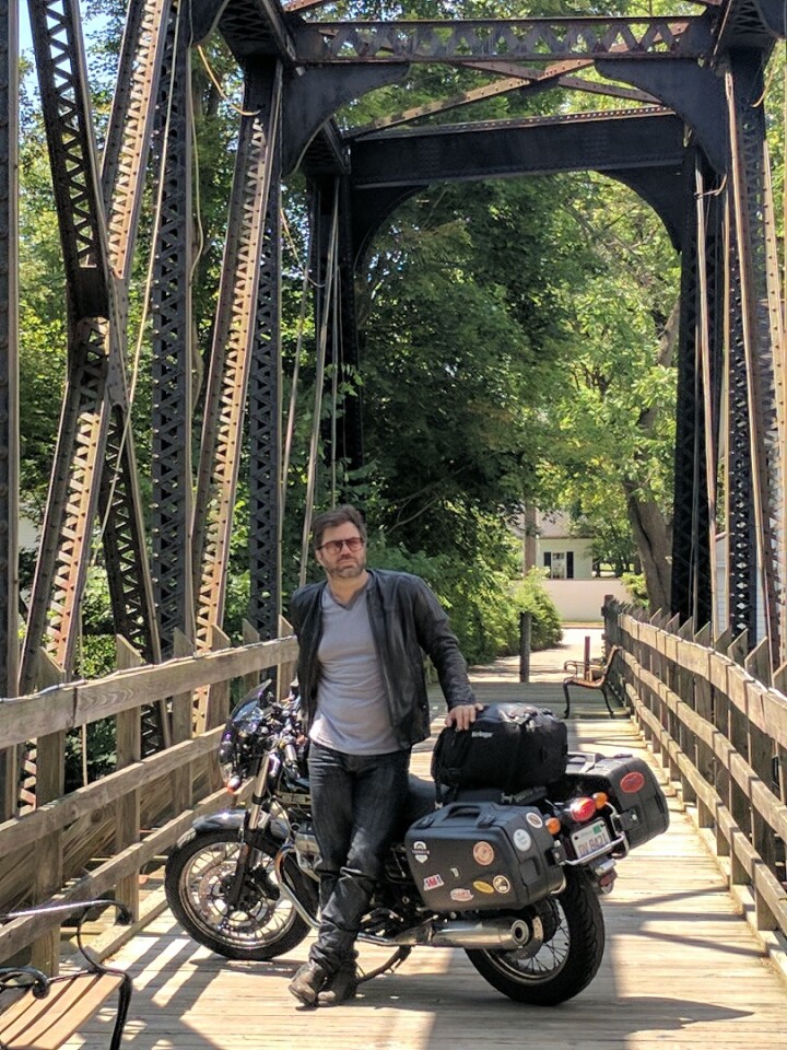 Twisted Road CEO Austin Rothbard, on a bridge with his Moto Guzzi