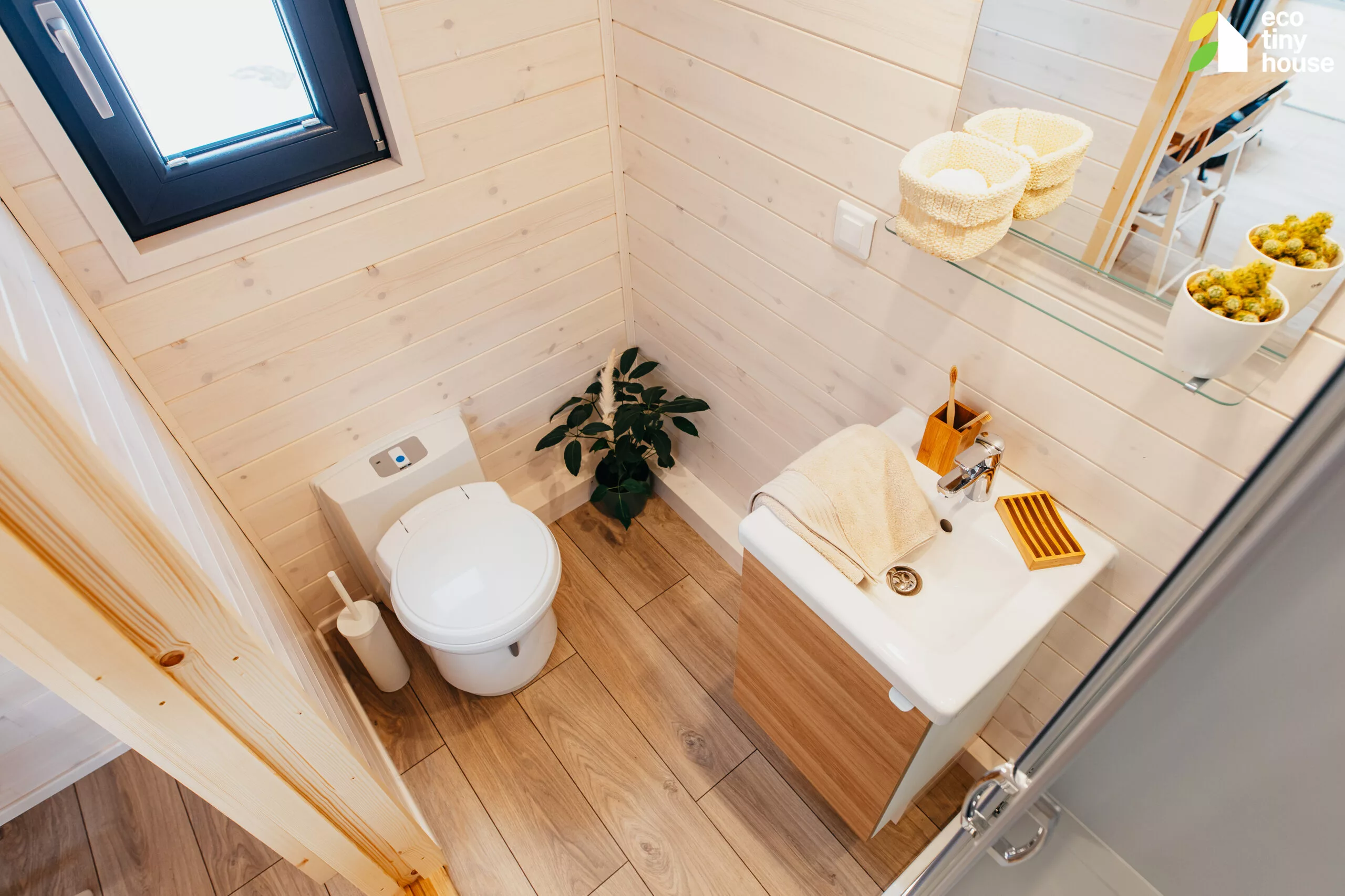 The Tiny Rubik's bathroom contains a glass-enclosed shower, a vanity sink, and a composting toilet