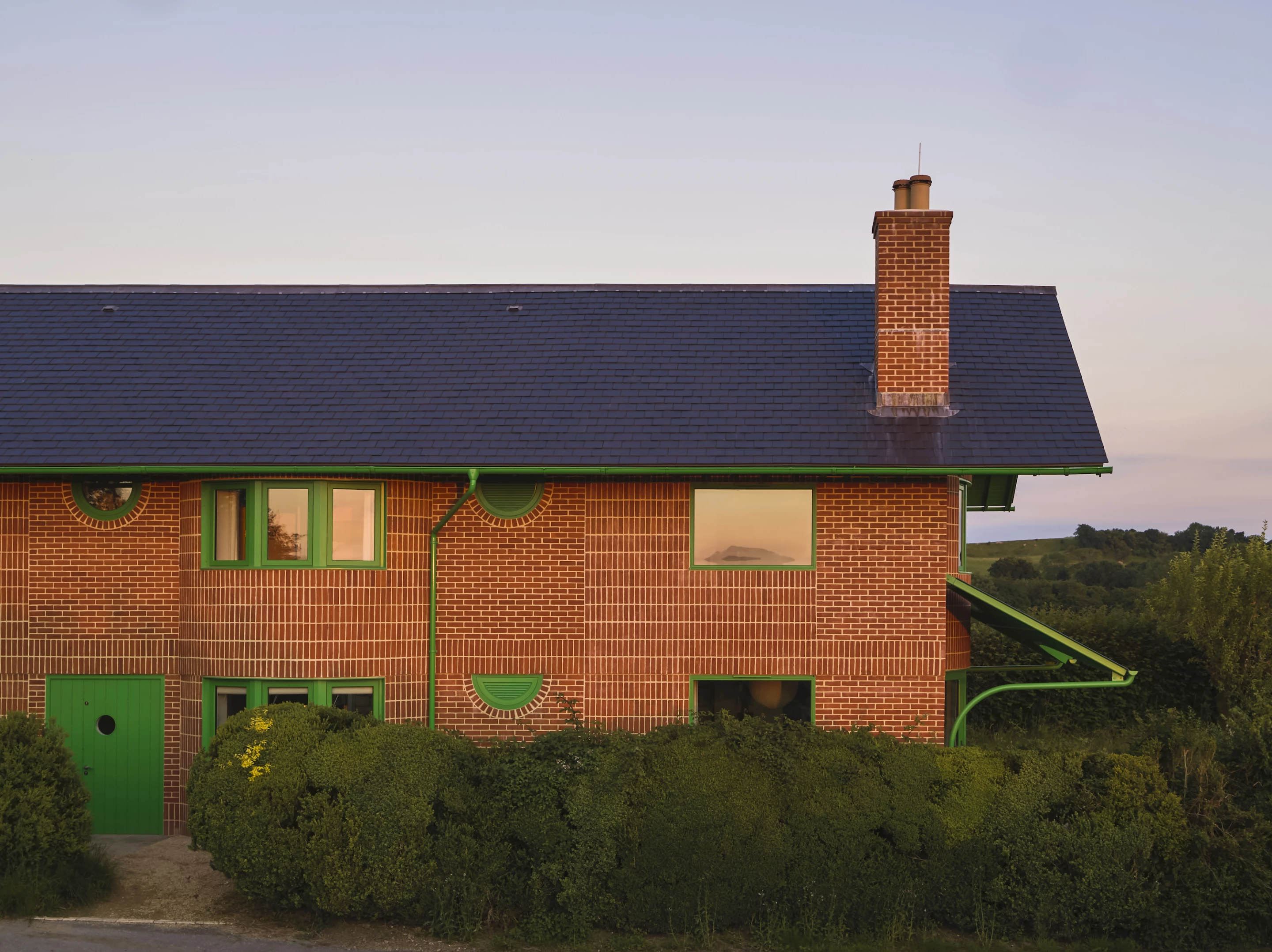 The Red House is defined by patterned red brickwork that's enlivened by contrasting bold green elements