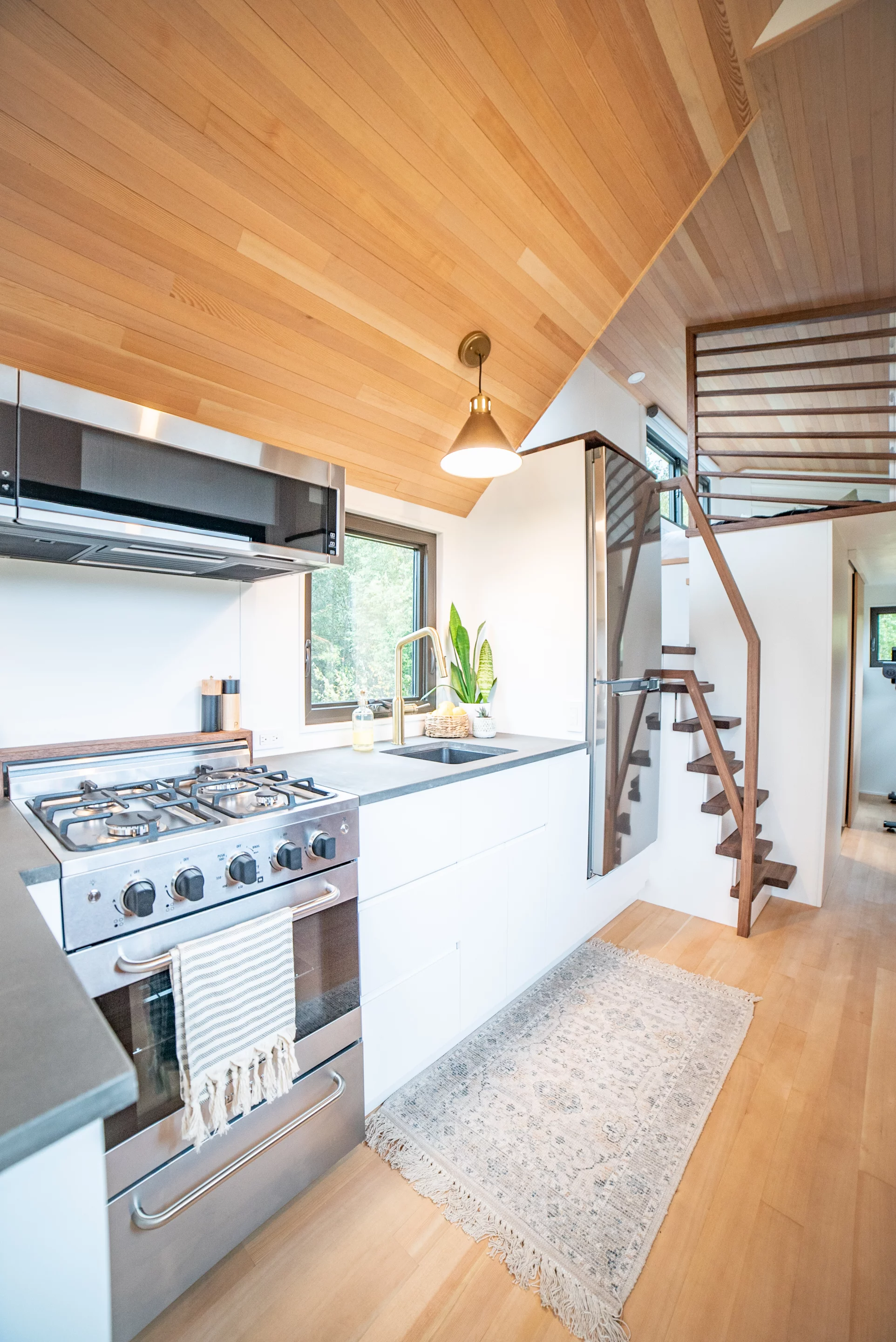 The Trahan Tiny House's kitchen is well-stocked for a tiny house and includes a four-burner propane-powered stove, an oven, and a full-sized fridge