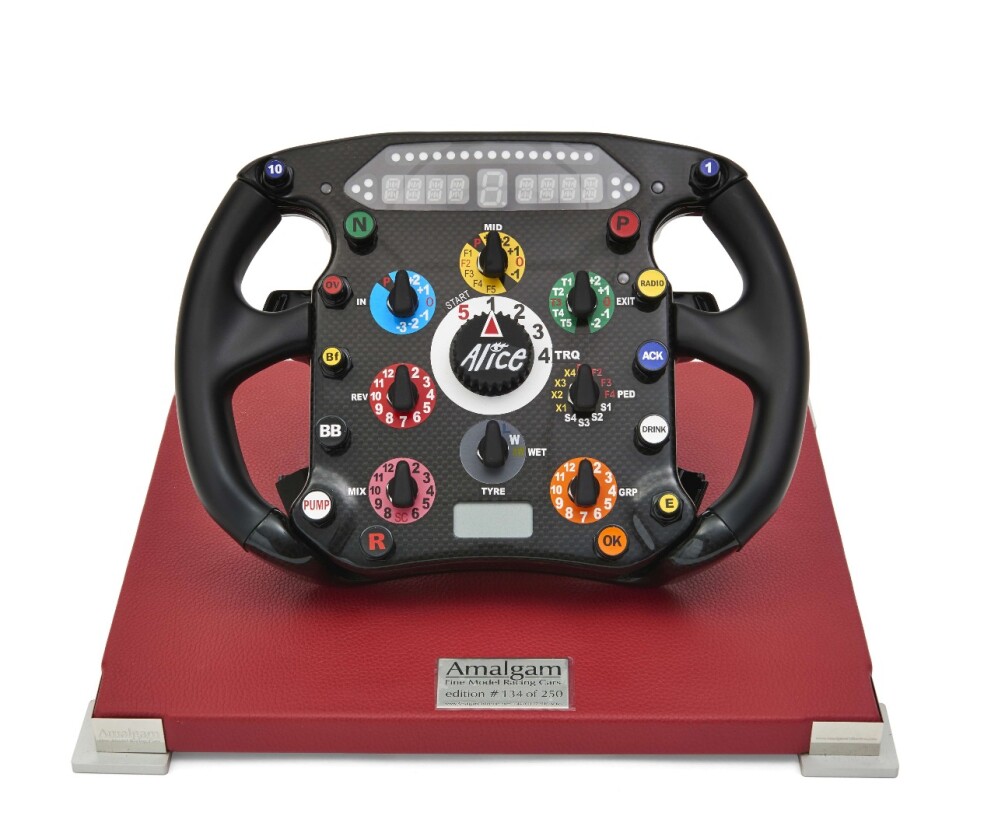 A limited edition (number 134 of 250) Ferrari F2008 Formula One steering wheel mounted on a red leather base, sold with a carrying case and a complete manual explaining the functions of the wheel. The F2008 designation indicates that this is identical to the steering wheels used in the Ferrari F2008 cars driven by Kimi Räikkönen and Felipe Massa during the 2008 season. Sold for $2,156 (€1,760)