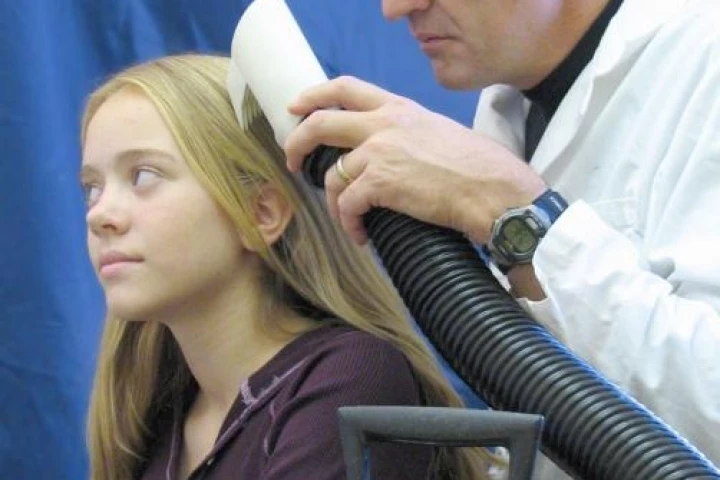 University of Utah biologist Dale Clayton demonstrates the the latest prototype of the LouseBuster on his daughter, Miriam. The new, chemical-free treatment kills almost all louse eggs and enough hatched lice to prevent them from reproducing, effectively