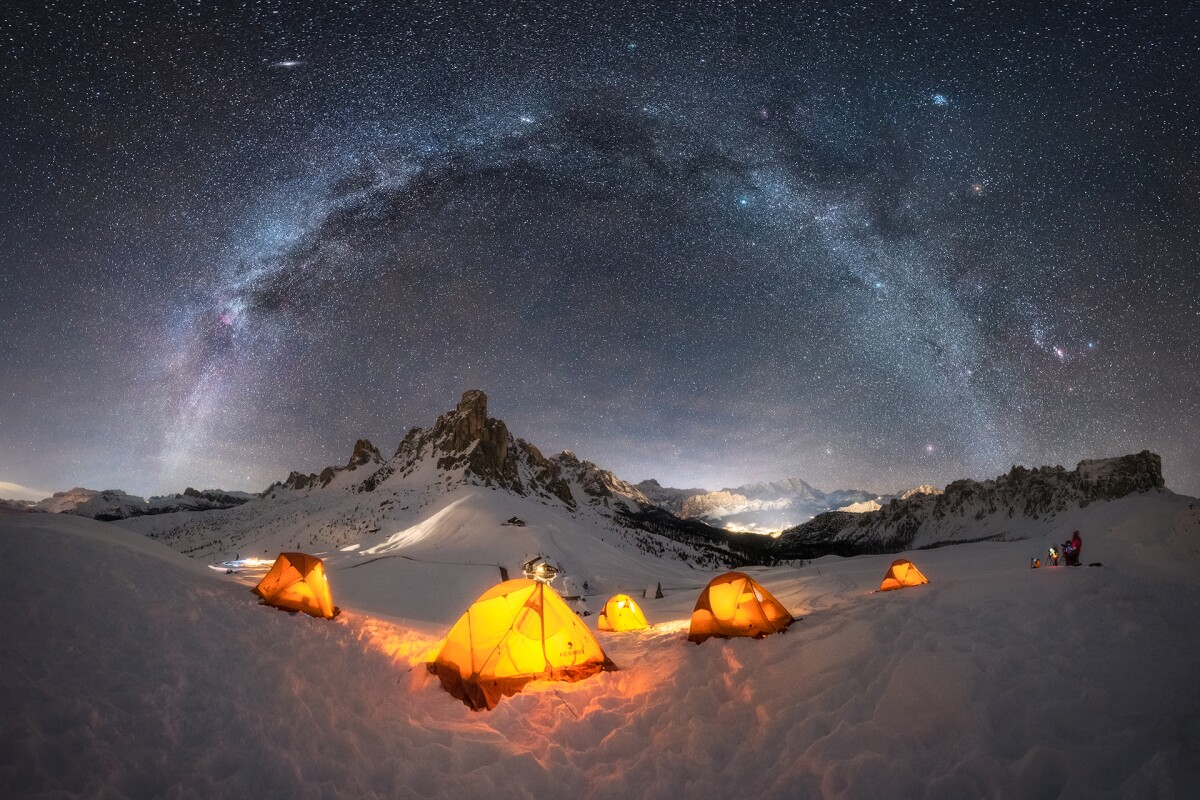 Base Camp, shot in the Dolomites, Italy. The warm glow of the tents contrasts the cool tones of the galaxy overhead.