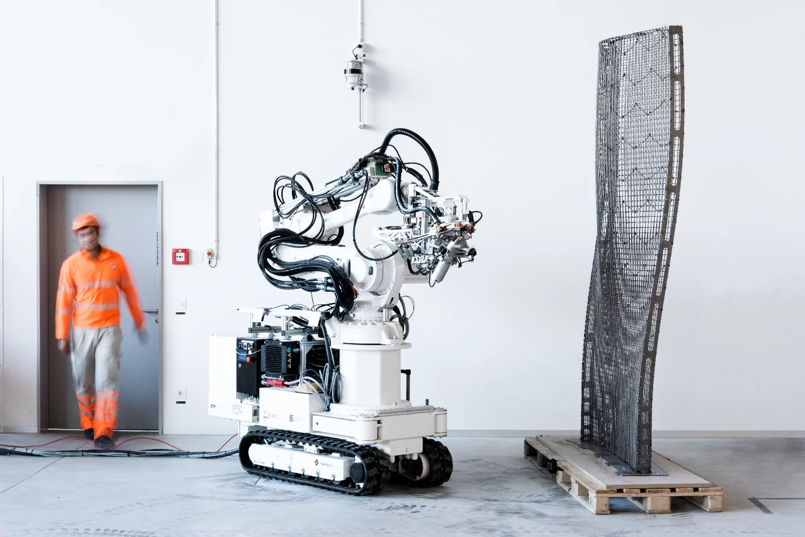 The two-meter tall fabrication robot uses a mesh mold toolhead to bend and weld steel rebar and make the wall framework