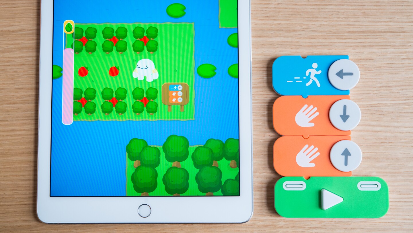 In the Osmo Coding game, users control a character called Awbie on a strawberry munching adventure using the physical code blocks